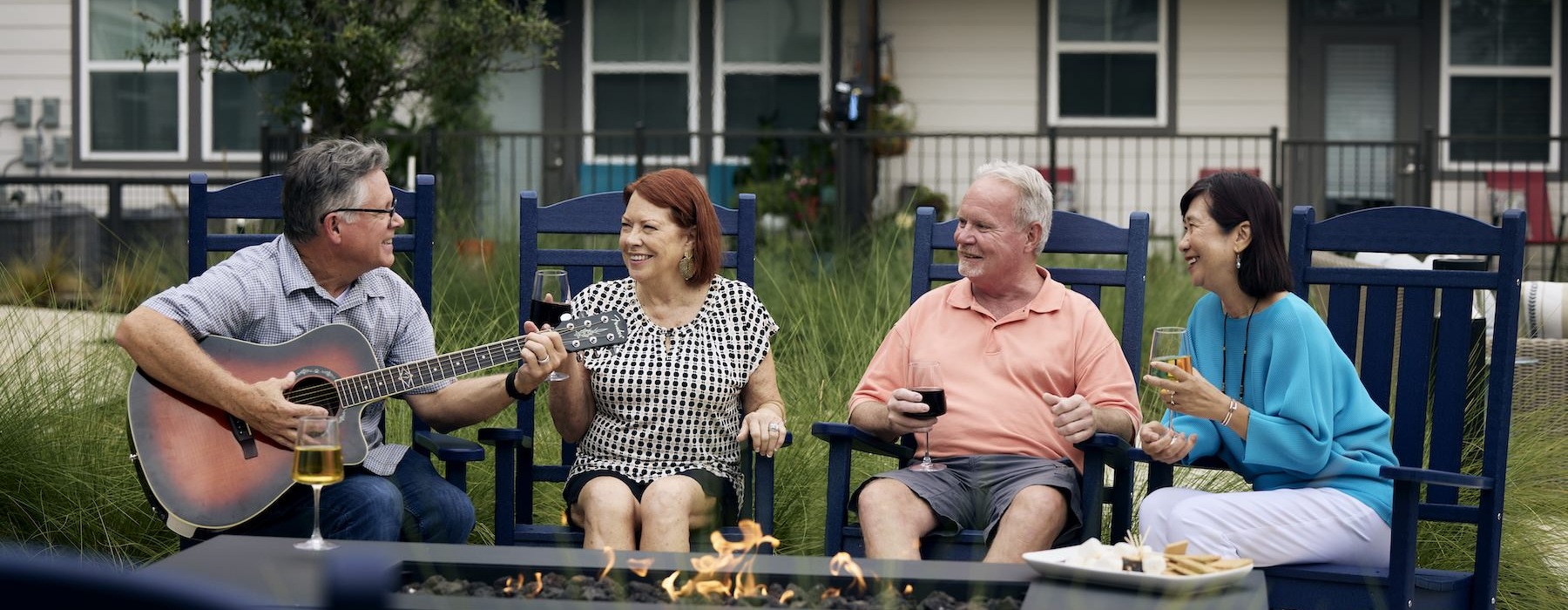 people sitting around fire and a man playing a guitar